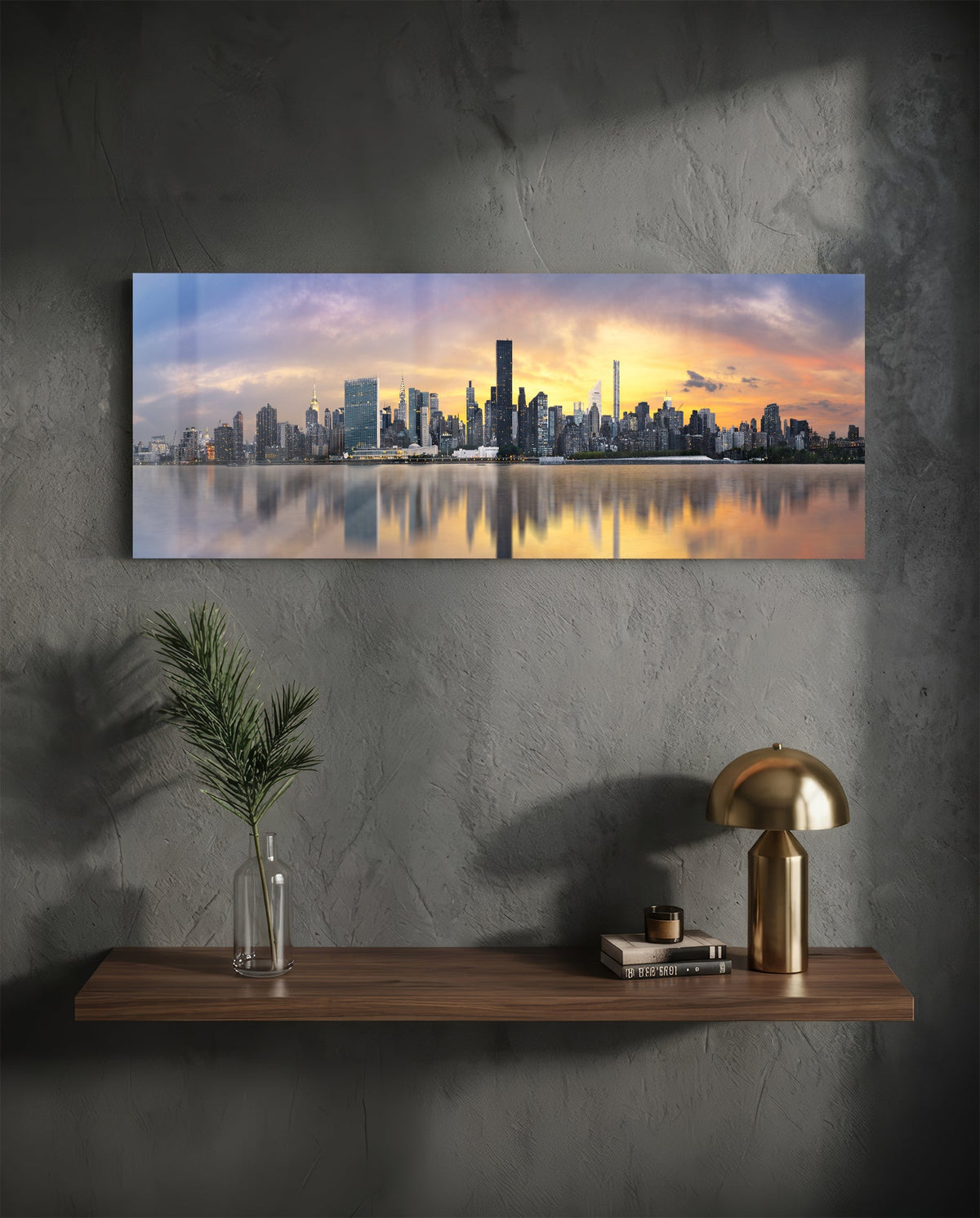 New York sunset skyline panoramic glass wall art on a dark wall above a shelf with a gold lamp