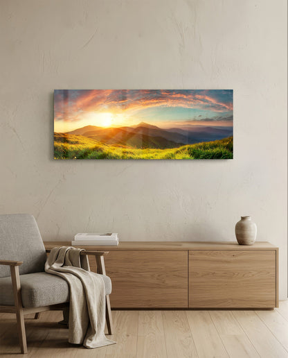 Golden sunset green hills panoramic glass wall art above a light wood sideboard beside a gray armchair