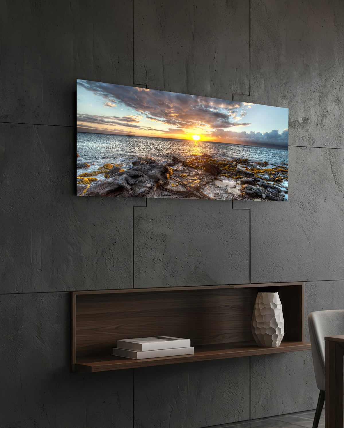 Rocky shore ocean sunset panoramic glass wall art above a floating wood shelf on a dark stone wall