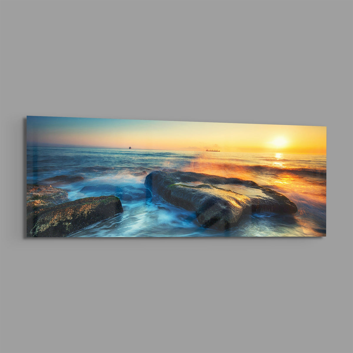 Mossy rocks sunrise sea panoramic glass print angled on a gray background