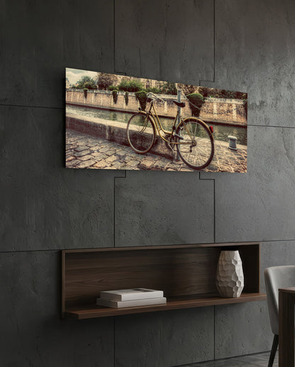 Vintage riverside bicycle glass wall art on a dark tiled wall above a recessed walnut shelf with a vase