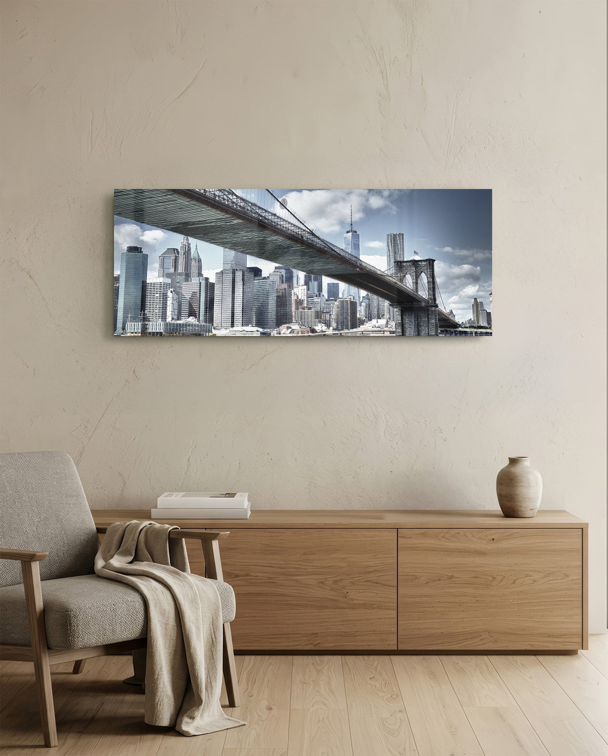 Brooklyn Bridge skyline panoramic glass wall art above a light wood sideboard and beige armchair