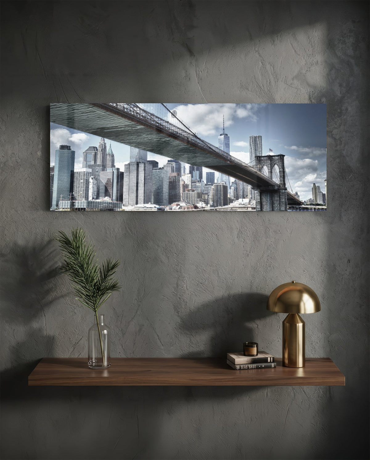 Brooklyn Bridge skyline panoramic glass wall art on a dark wall above a shelf with a gold lamp