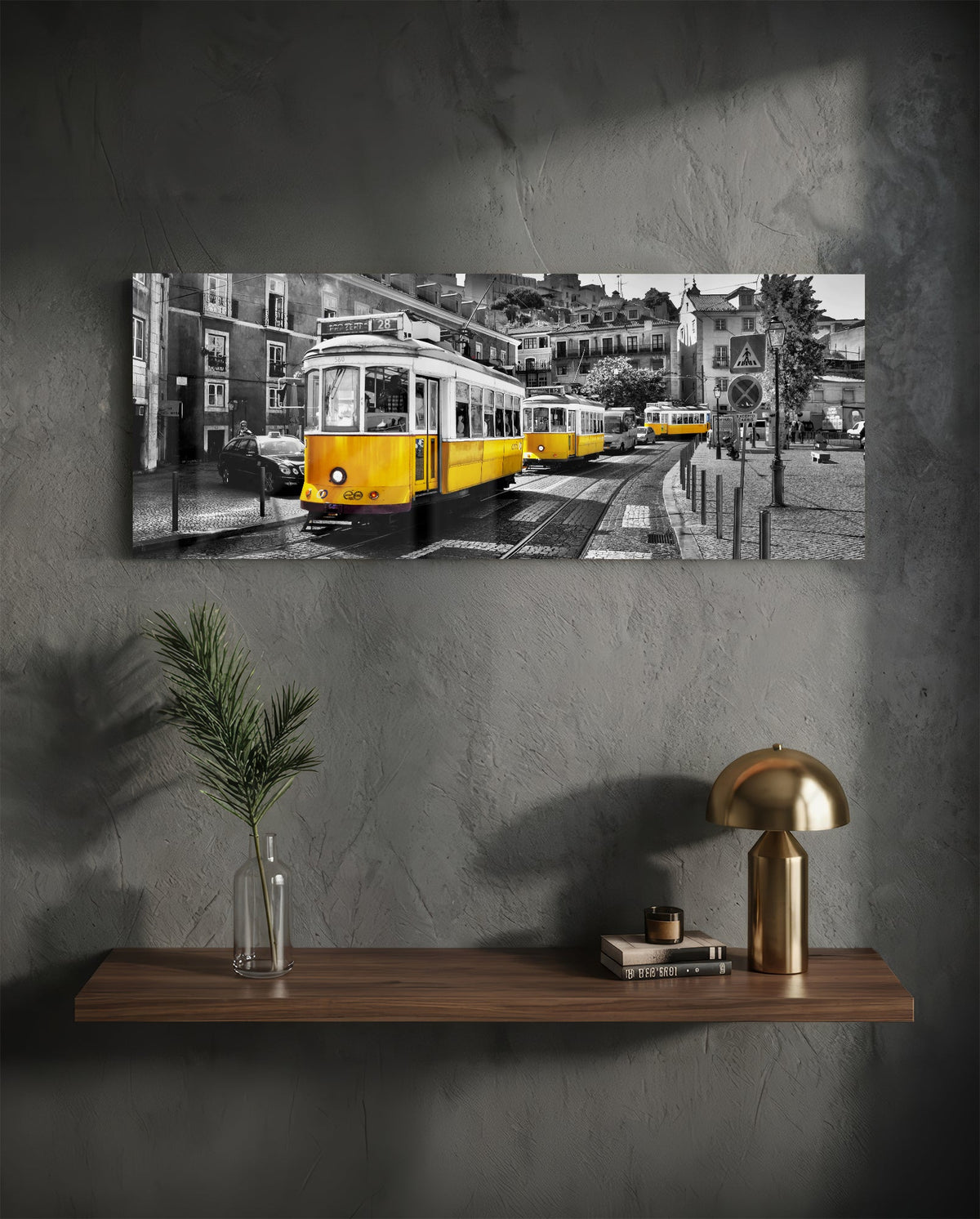 Yellow tram panoramic glass wall art on a dark wall above a floating shelf with a gold lamp