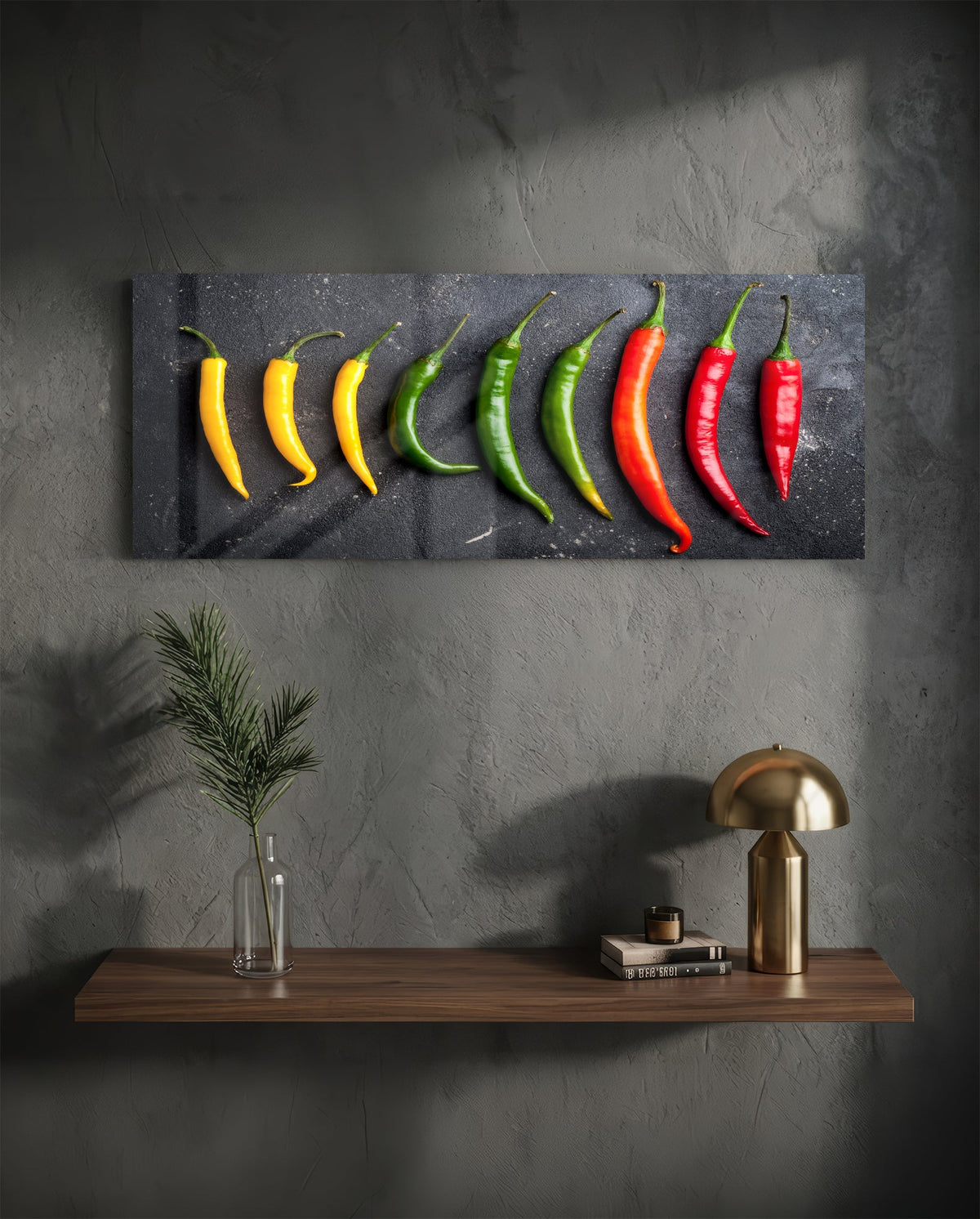 Chili peppers on black slate glass wall art on a charcoal wall above a floating shelf with a brass lamp and greenery