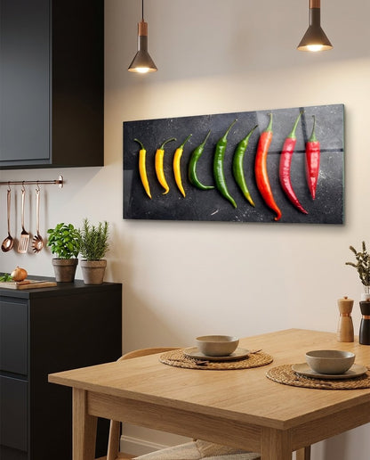 Chili peppers glass wall art in a kitchen above a wooden dining table under pendant lights