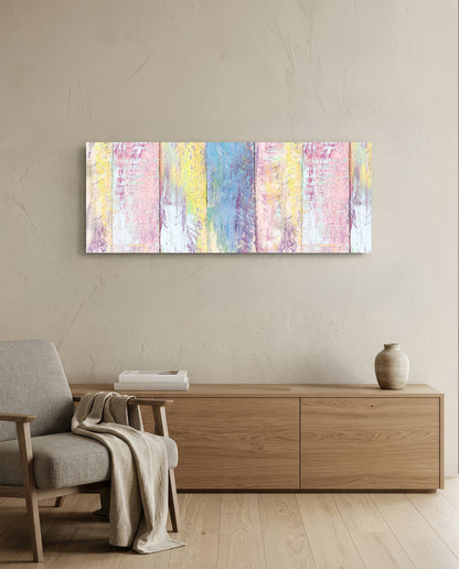 Pastel painted wood planks glass wall art above a light wood sideboard beside a gray armchair with a throw