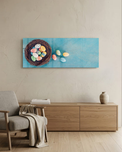 Easter eggs in a nest glass wall art above a light wood sideboard beside a gray armchair with a throw