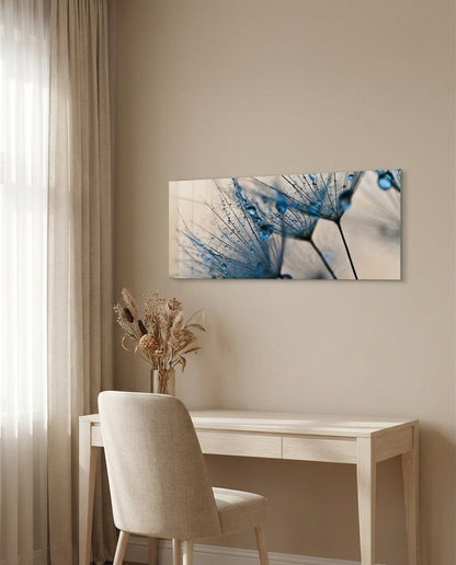 Panoramic blue dandelion seeds glass wall art above a light wood desk beside sheer curtains and dried flowers