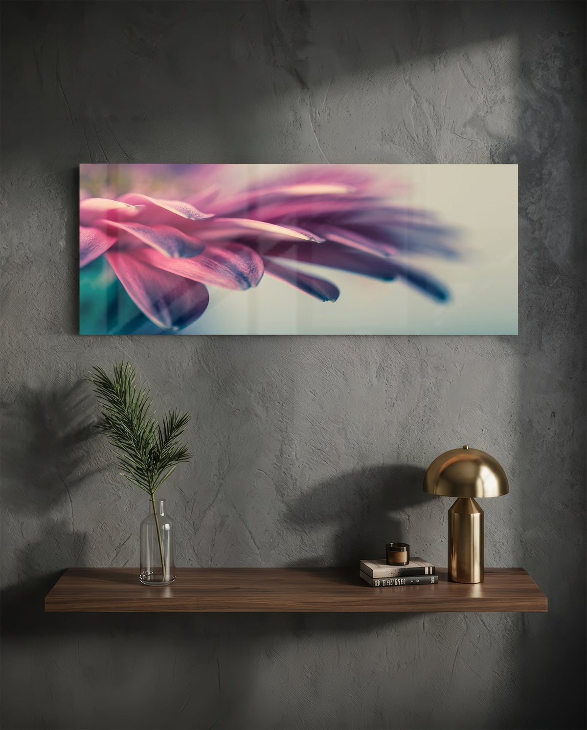 Pink flower petal macro glass wall art on a charcoal wall above a floating shelf with a brass lamp and greenery