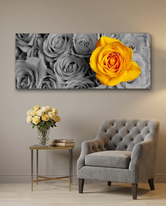 One orange and yellow rose standing out from a bed of gray roses, panoramic glass wall art above a gray tufted armchair