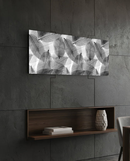 Black and white skeleton leaves glass wall art on a dark slate wall above a walnut floating shelf