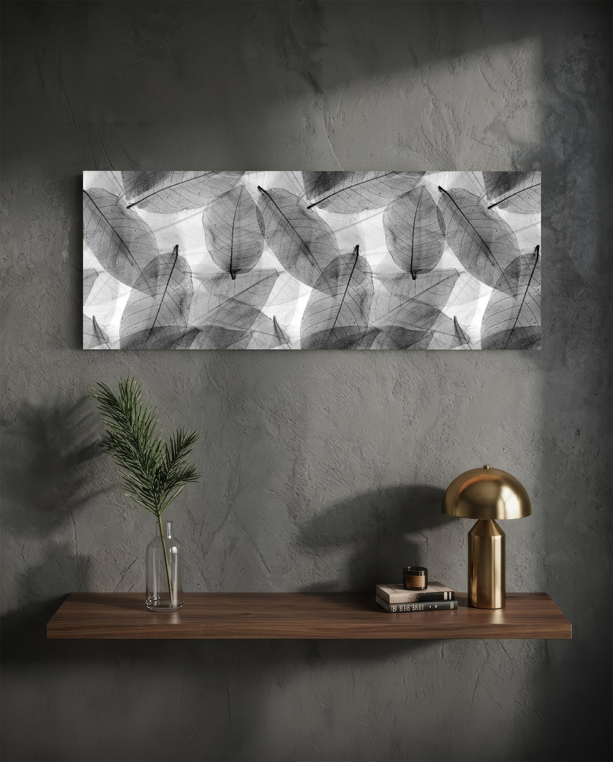 Black and white skeleton leaves glass wall art above a floating shelf with a brass lamp and a plant in a vase