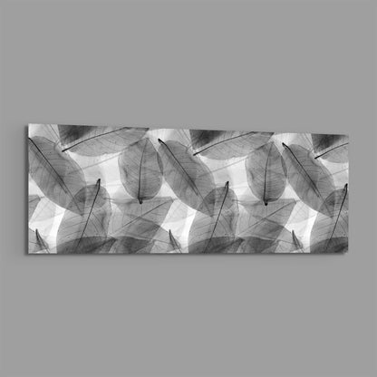 Black and white skeleton leaves panoramic glass wall art shown on a plain gray background