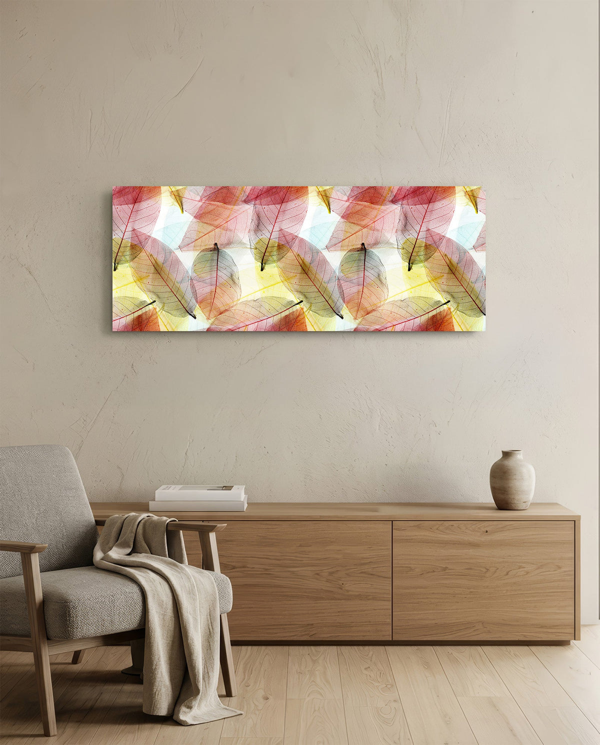 Pink and gold skeleton leaves glass wall art above an oak sideboard beside a wooden armchair with a throw