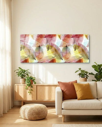 Pink, peach and gold skeleton leaves panoramic glass wall art above a cream sofa with rust and mustard pillows