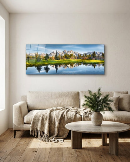 Mountain lake reflection glass wall art above a cream sofa and a round wooden coffee table