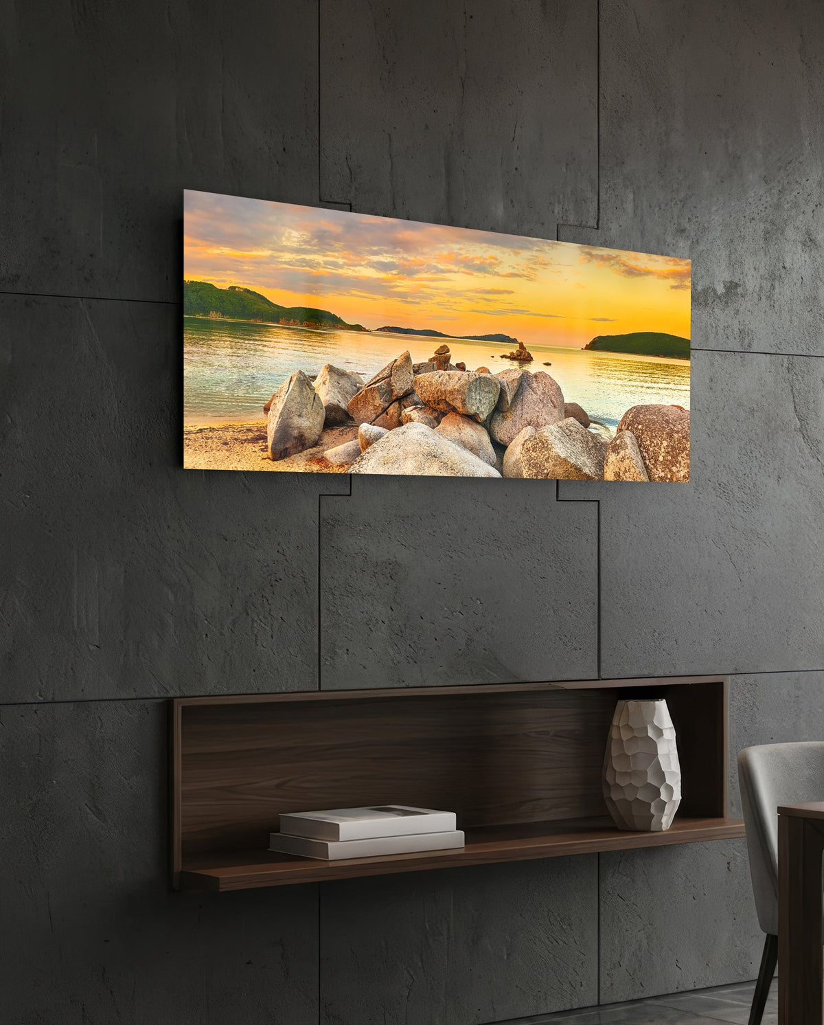 Golden sunset boulder bay glass wall art above a dark wood wall shelf on a charcoal paneled wall