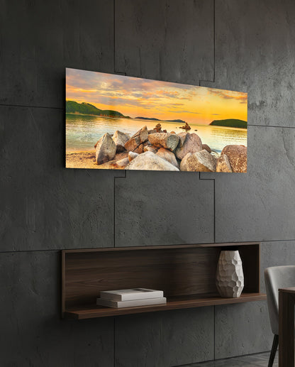 Golden sunset boulder bay glass wall art above a dark wood wall shelf on a charcoal paneled wall
