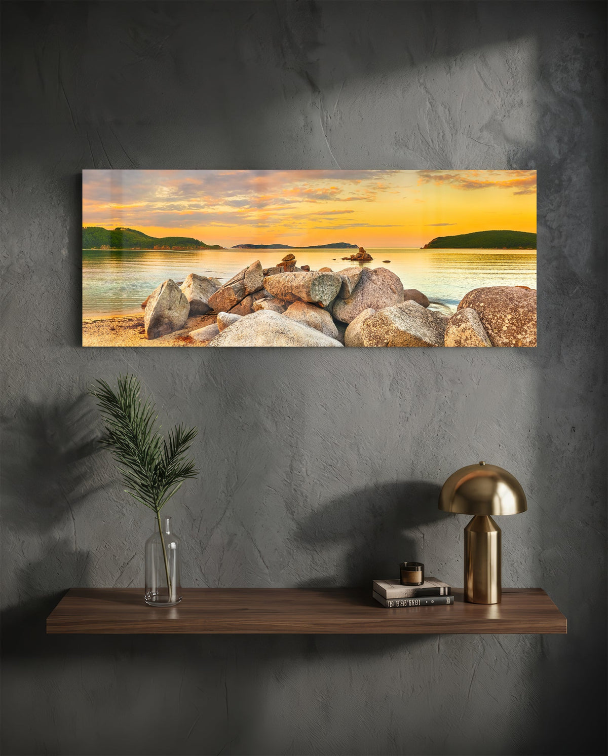 Golden sunset boulder bay glass wall art above a floating walnut shelf with a brass lamp