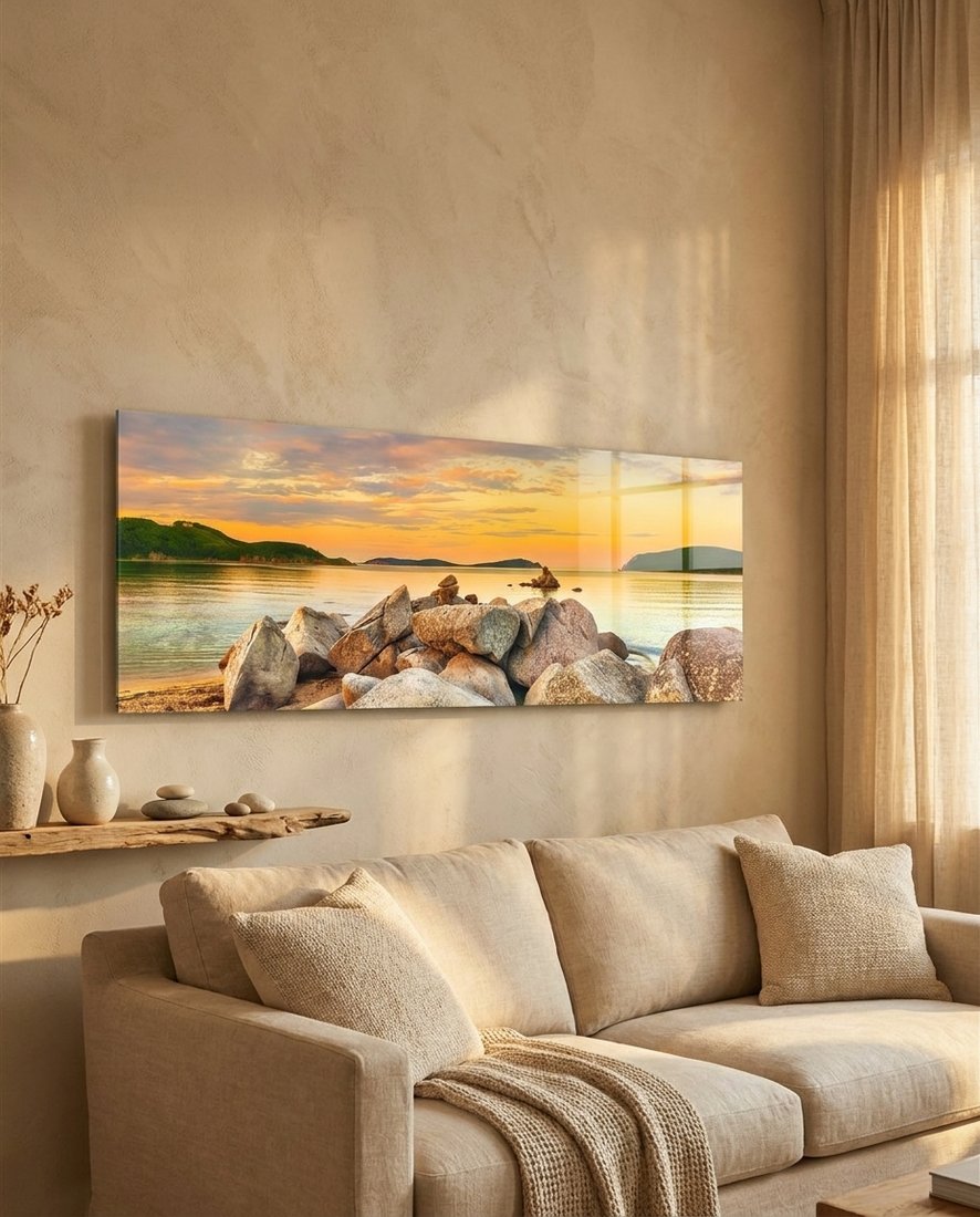 Golden sunset boulder bay panoramic glass wall art above a cream sofa in a warm beige room