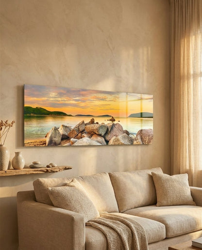 Golden sunset boulder bay panoramic glass wall art above a cream sofa in a warm beige room