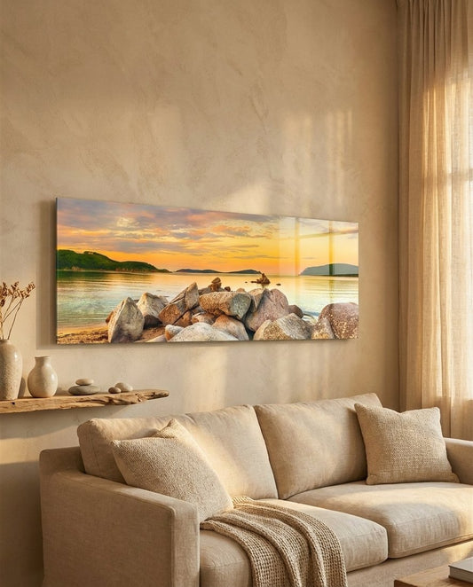 Golden sunset boulder bay panoramic glass wall art above a cream sofa in a warm beige room