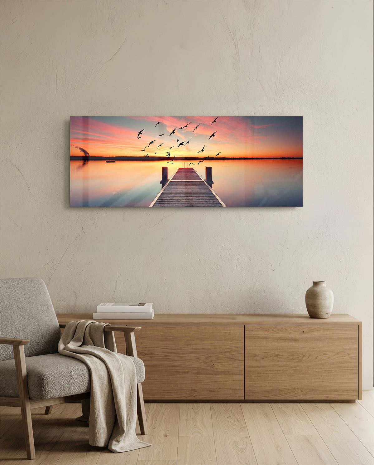 Sunset pier panoramic glass wall art above an oak sideboard beside a gray armchair