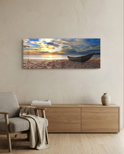 Wooden boat on a sandy beach at sunset glass wall art above a light oak sideboard beside a cream armchair