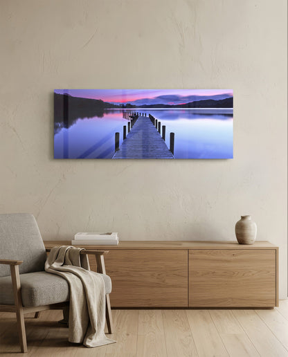 Purple twilight lake jetty glass wall art above a light oak sideboard beside a cream armchair