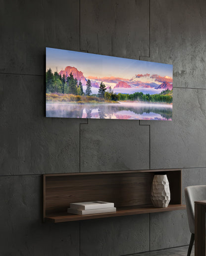Pink dawn mountain lake panoramic glass wall art above a floating wood shelf on a dark stone wall