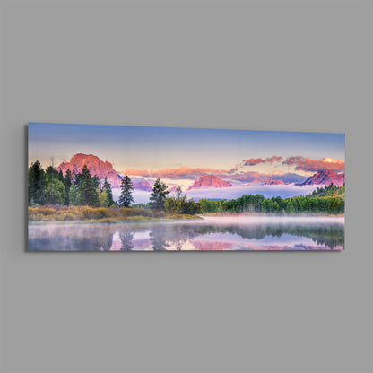 Pink dawn mountain lake panoramic glass wall art on a plain gray wall
