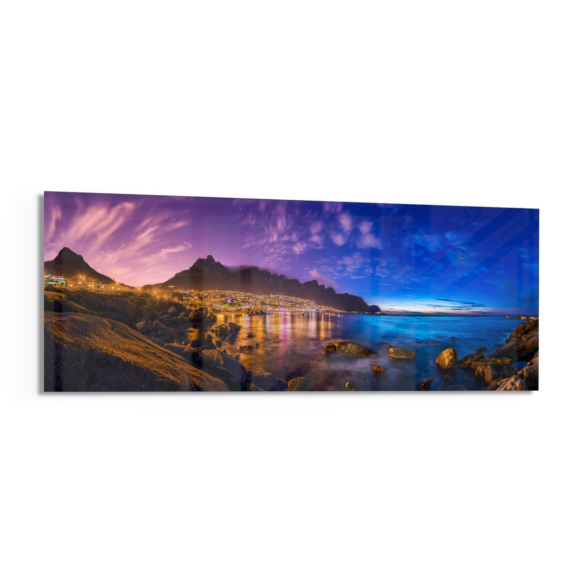Coastal town at dusk panoramic glass wall art shown at an angle on a white background