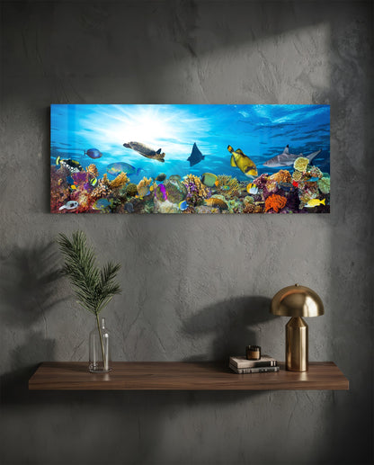 Coral reef sea turtle glass wall art above a floating walnut shelf with a brass lamp