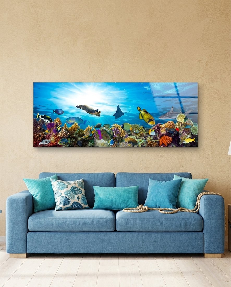 Coral reef sea turtle panoramic glass wall art above a blue sofa with teal cushions on a sand-colored wall