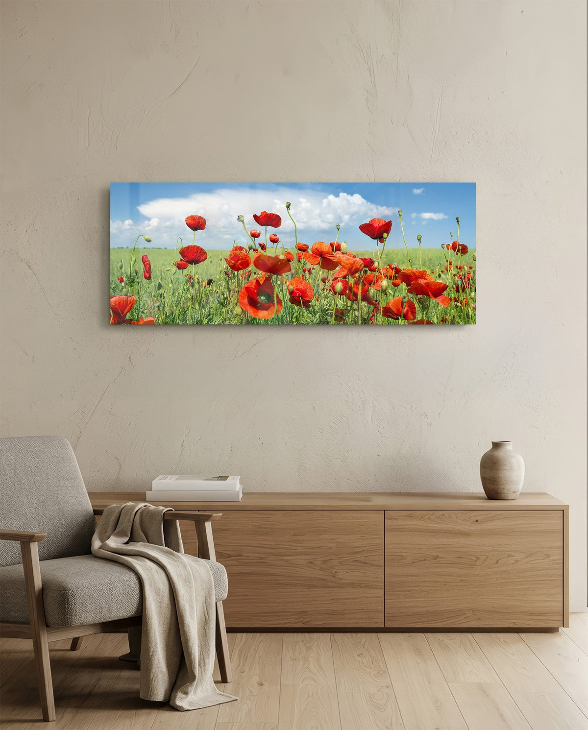 Red poppy field glass wall art above an oak sideboard beside a wooden armchair with a throw