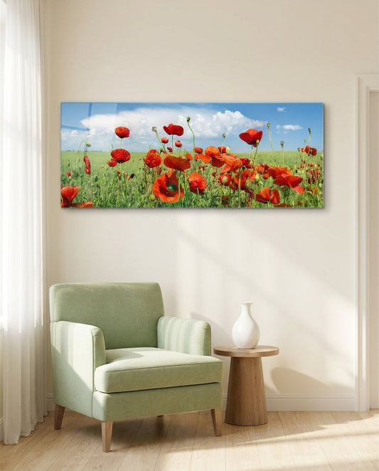 Red poppies across a green meadow under a blue sky with white clouds, panoramic glass wall art above a sage green armchair