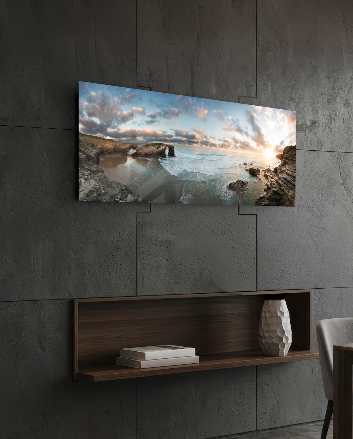 Rock arch coastline at sunset glass wall art above a dark wood wall shelf on a charcoal paneled wall