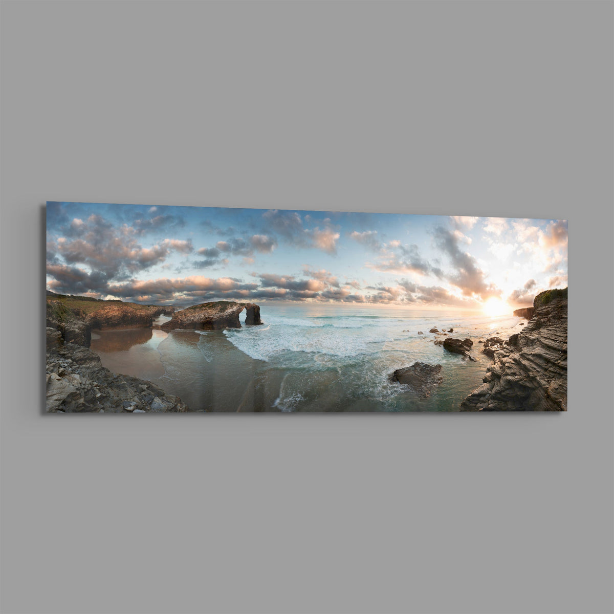 Rock arch coastline at sunset panoramic glass print angled on a gray background