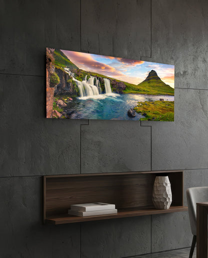 Waterfall and cone mountain panoramic glass wall art above a floating wood shelf on a dark stone wall