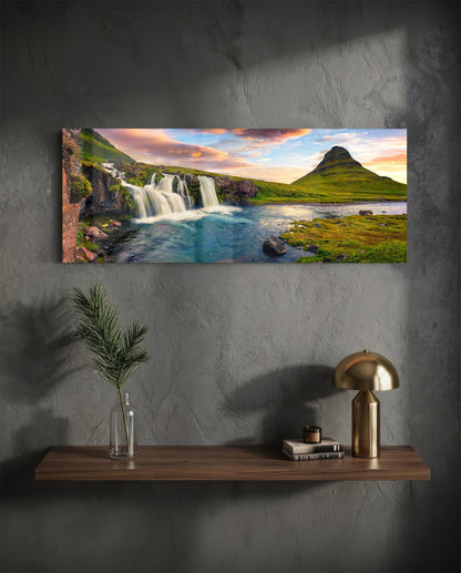 Waterfall and cone mountain panoramic glass wall art above a wood shelf with a brass lamp on a dark wall