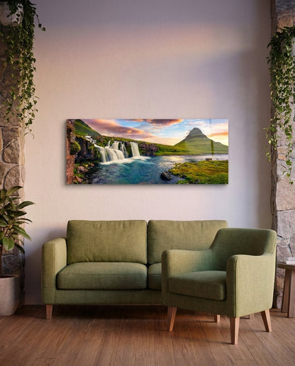 Waterfall and cone mountain panoramic glass wall art above a green sofa and armchair on a wood floor