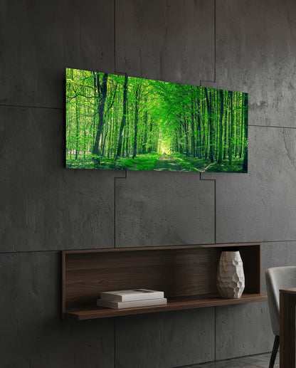Green forest path glass wall art on a dark slate wall above a walnut floating shelf