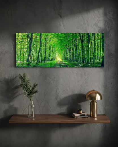 Green forest path glass wall art above a floating shelf with a brass lamp and a plant in a vase