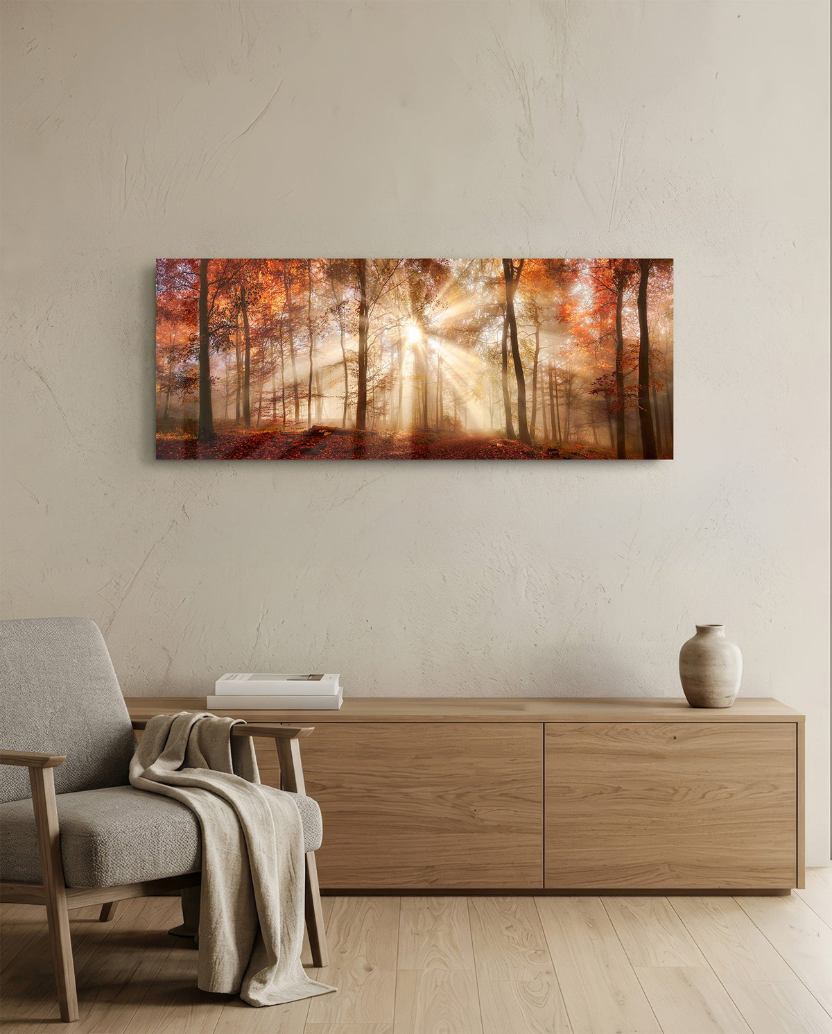 Autumn forest sun rays panoramic glass wall art above a light wood sideboard beside a gray armchair