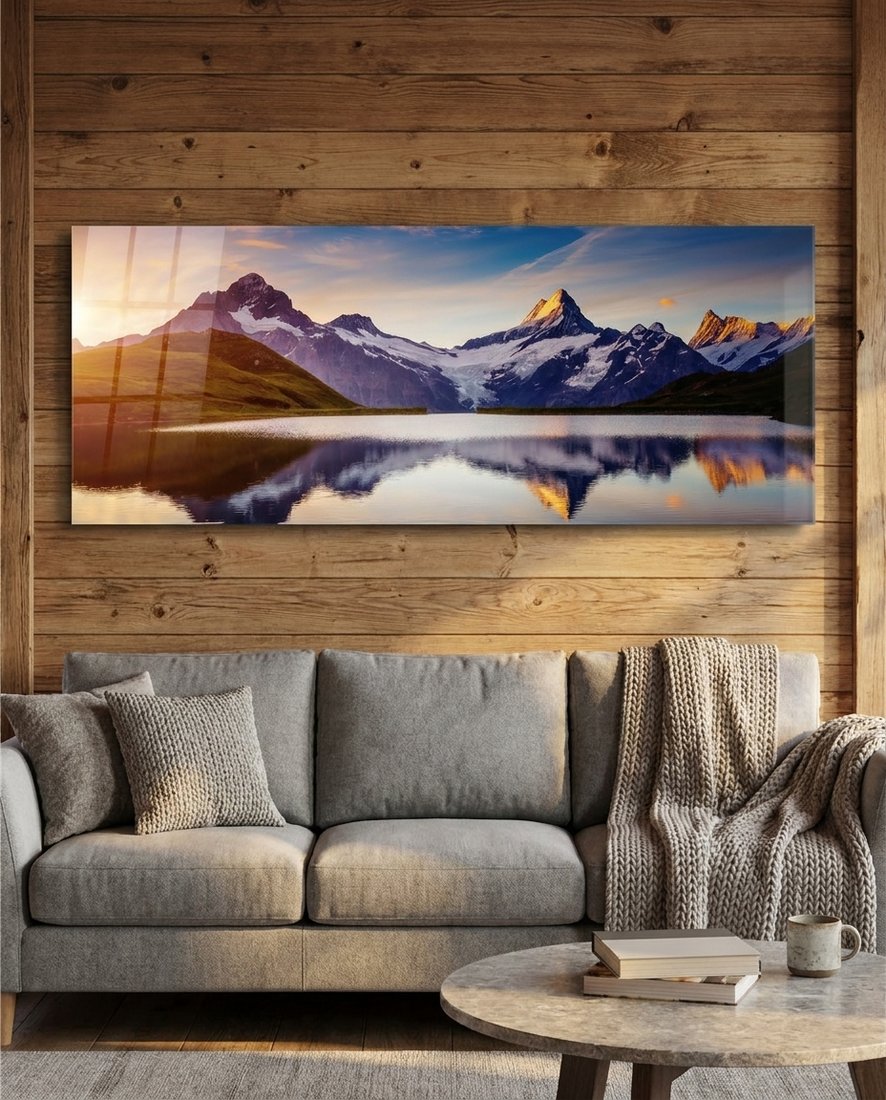 Sunrise alpine peaks lake panoramic glass wall art on a wood plank wall above a gray sofa