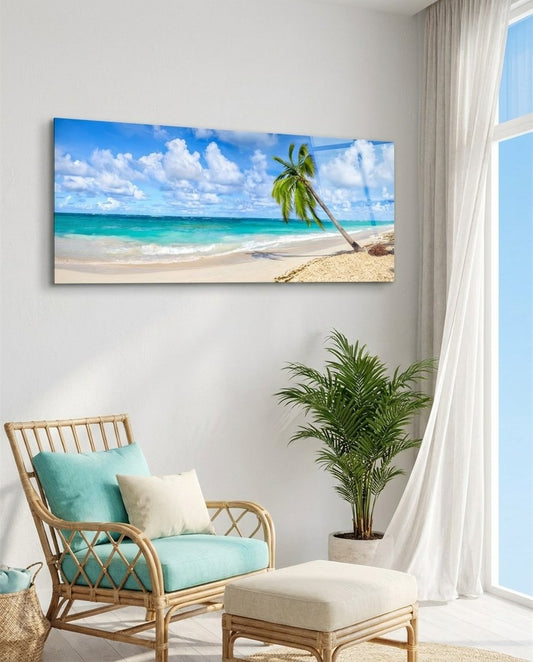 Tropical palm tree beach panoramic glass wall art beside a rattan lounge chair and a large plant in a bright room