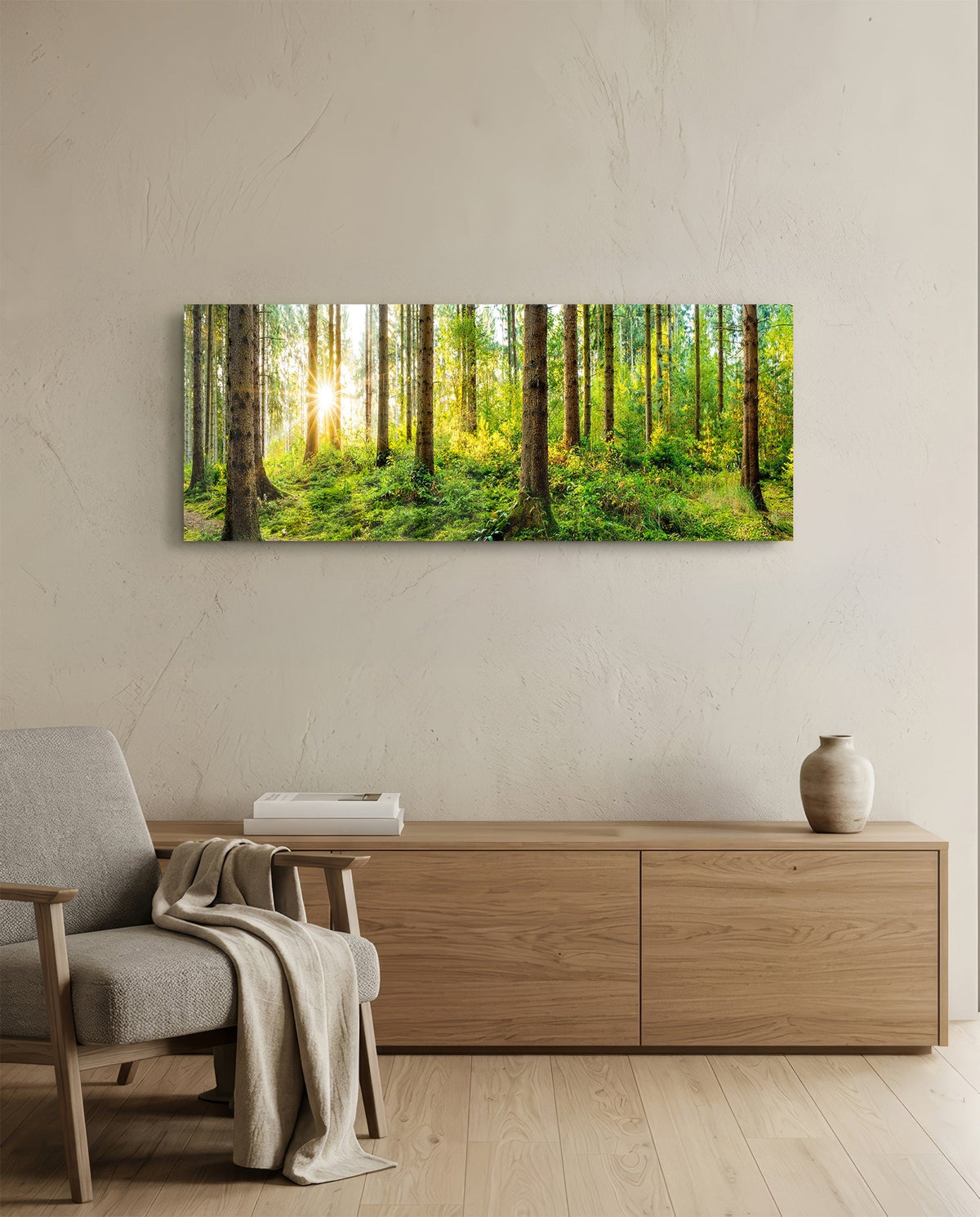Sunlit mossy pine forest panoramic glass wall art above a light wood sideboard beside a gray armchair