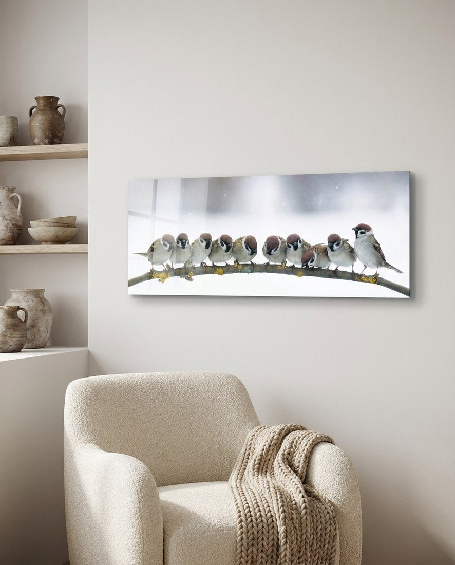 Snowy sparrow flock panoramic glass wall art above a boucle armchair beside shelves with clay pots