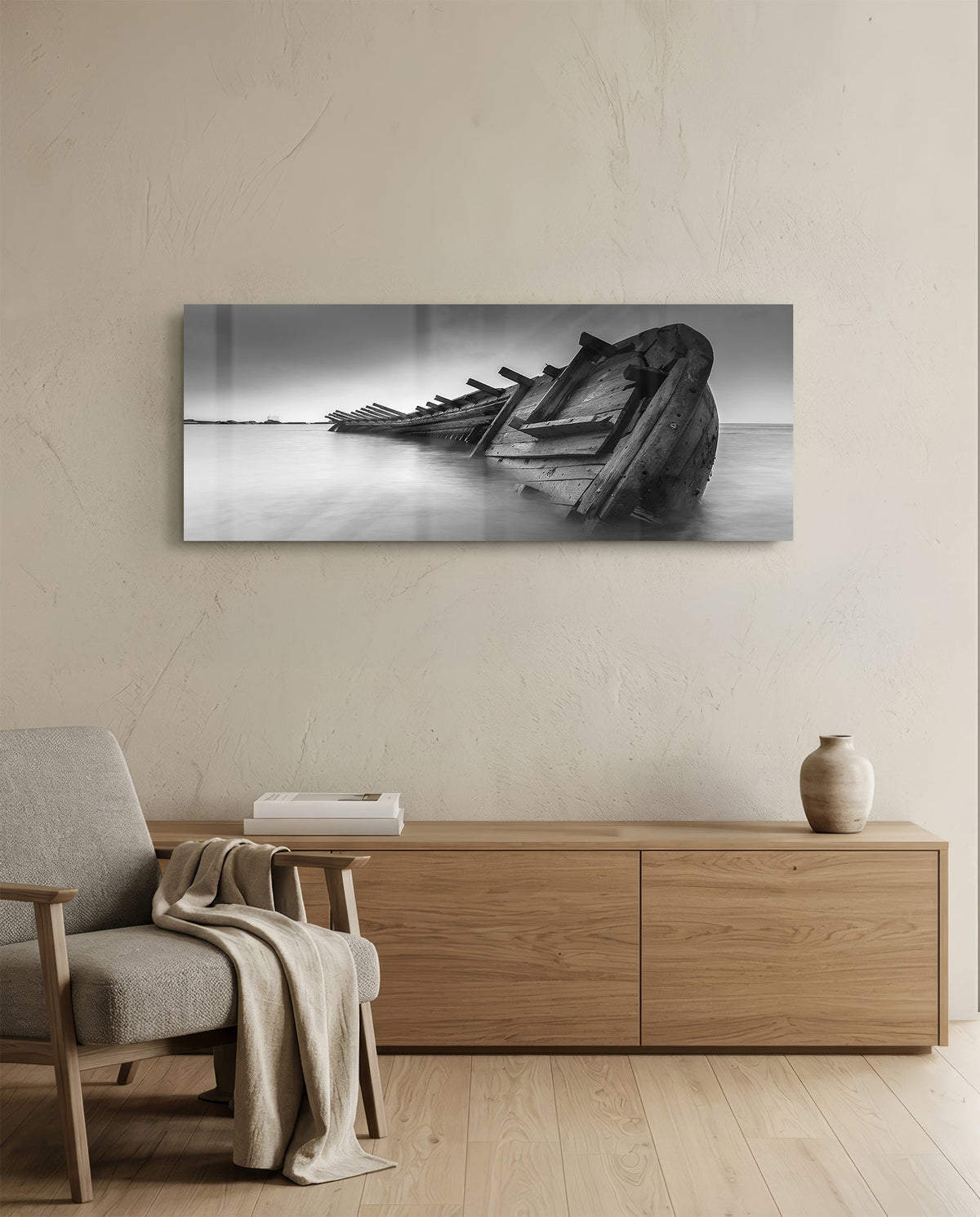 Black and white shipwreck glass wall art above a light oak sideboard beside a cream armchair